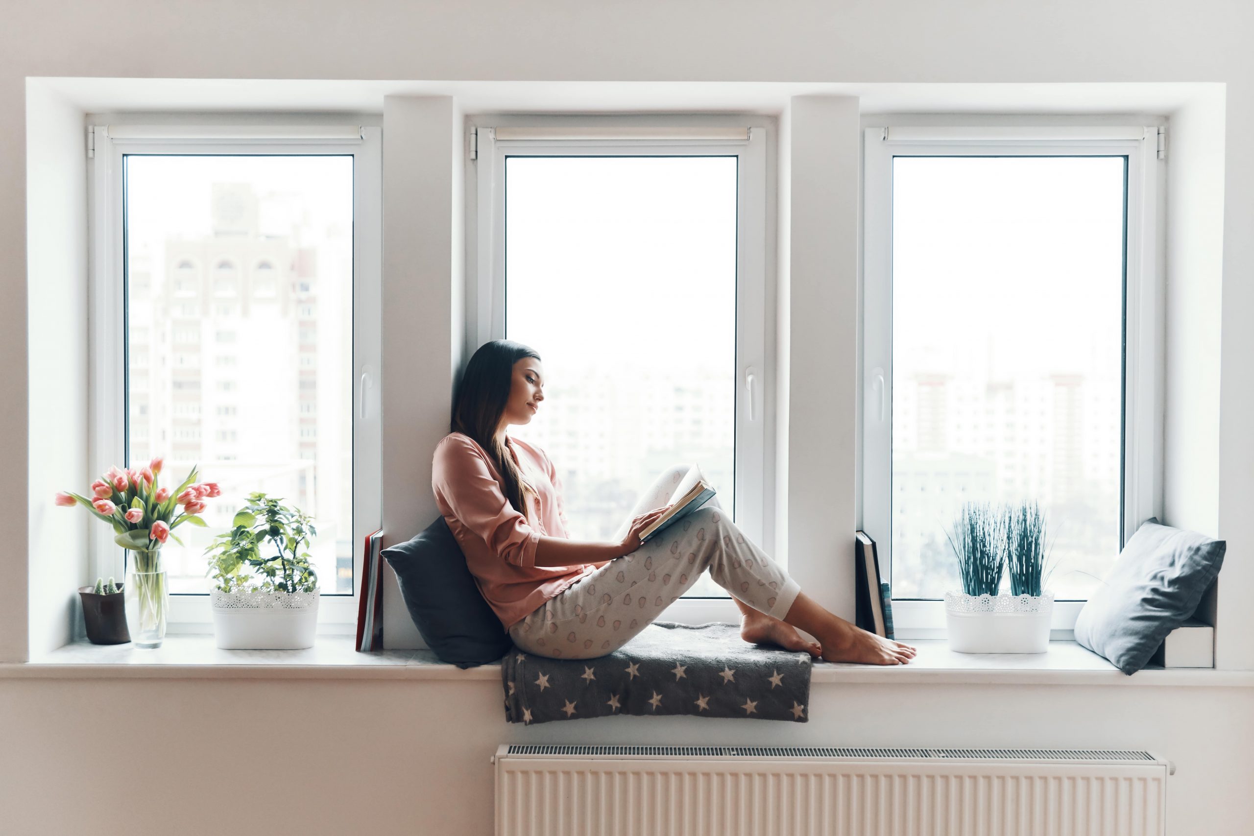 carefree-young-woman-in-cozy-pajamas-reading-a-boo-5BTWBF6-min